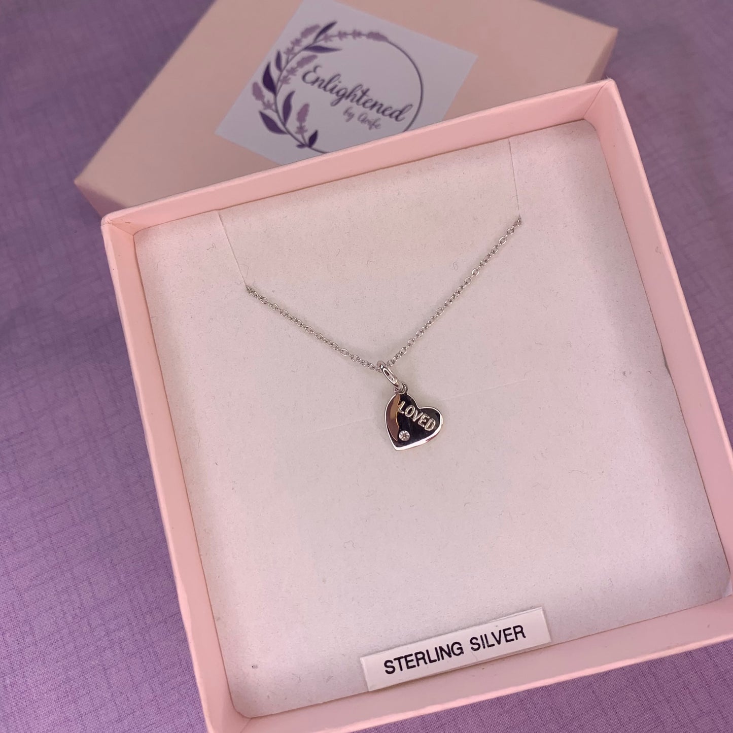 Rhodium plated sterling silver heart pendant with CZ engraved with the affirmation 'loved'. A thoughtful gift, great as a mental health gift or to promote self-love