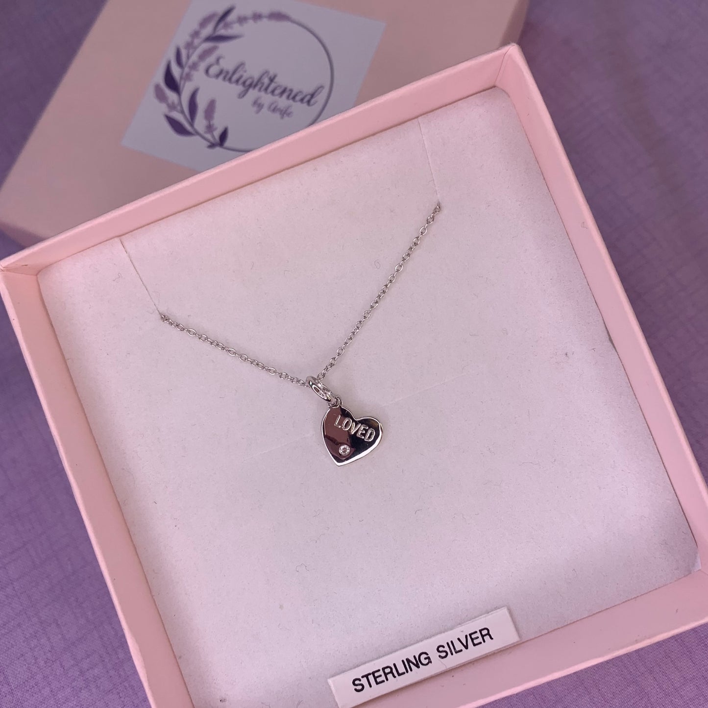 Rhodium plated sterling silver heart pendant with CZ engraved with the affirmation 'loved'. A thoughtful gift, great as a mental health gift or to promote self-love